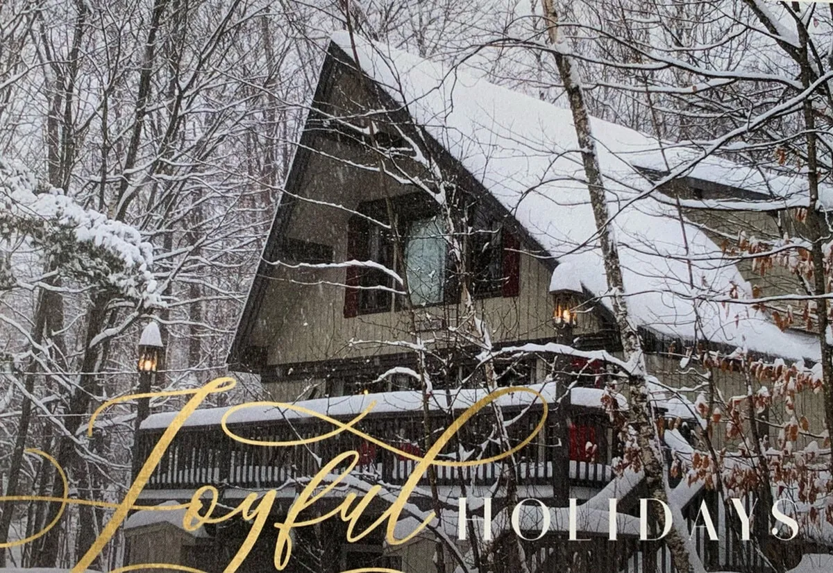 A wintery exterior scene shows a snow-covered roof and wooden balcony nestled among trees. The setting radiates warmth and coziness, suggesting festive family gatherings and après-ski relaxation after a day on the slopes.