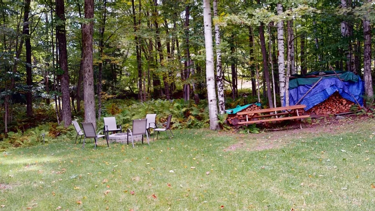 A cozy, inviting fire pit is surrounded by chairs and a stack of wood, set in a natural outdoor environment. The space is clearly designed for gathering, storytelling, and enjoying evenings under the stars, reflecting the section’s emphasis on communal outdoor experiences and the magical atmosphere created by the property’s secluded yard.